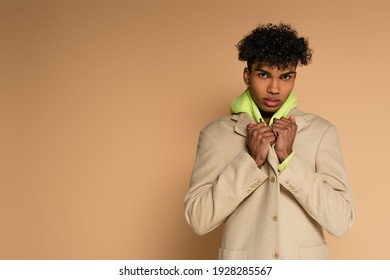 Young African American Man Adjusting Blazer On Beige