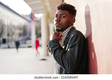 Young African American man adjusting the collar of a plaid shirt looking at camera. - Powered by Shutterstock