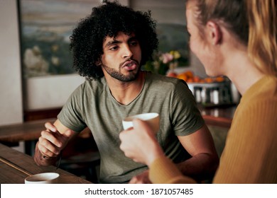 Young African American man with an afro in serious conversation with woman while sitting in a cafe and drinking coffee - two diverse friends chatting in a coffee shop  - Powered by Shutterstock