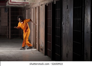 A young african american man with an afro is sneaking out of a prison cell. Vertical shot.