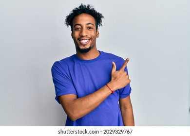 Young African American Man With Beard Wearing Casual Blue T Shirt Smiling Cheerful Pointing With Hand And Finger Up To The Side 