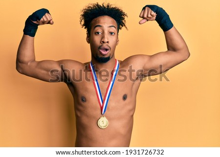 Young african american man with beard wearing first place medal on boxing competition afraid and shocked with surprise and amazed expression, fear and excited face. 