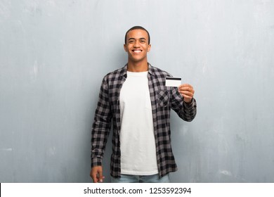 Young African American Man With Checkered Shirt Holding A Credit Card