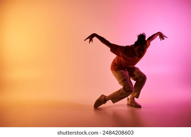 A young African American man dances on a colorful gradient background, showcasing his skill and passion for movement. - Powered by Shutterstock