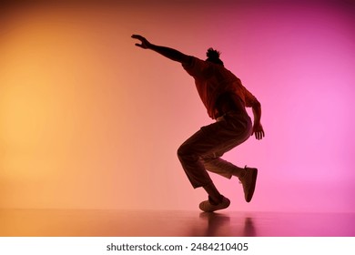 A young African American man dances against a vibrant gradient background. He is captured in mid-air, showcasing his dynamic movements. - Powered by Shutterstock