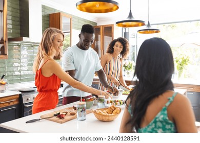 Young African American man and diverse group of women enjoy preparing food together. They are in a bright kitchen, sharing a joyful cooking experience. - Powered by Shutterstock