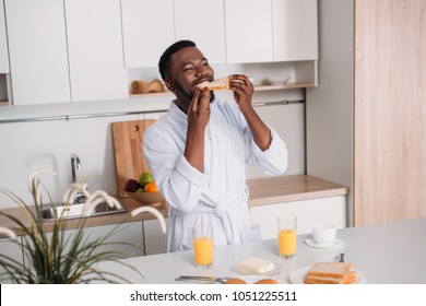 Young African American Man Eating Toast In Kitchen