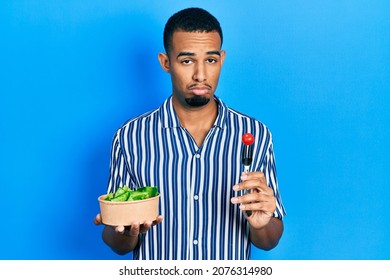 Young African American Man Eating Salad Depressed And Worry For Distress, Crying Angry And Afraid. Sad Expression. 