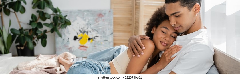 Young African American Man Embracing Seductive Woman Smiling With Closed Eyes In Bedroom, Banner