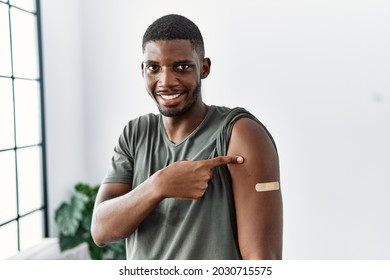 Young African American Man Getting Vaccine Showing Arm With Band Aid Smiling Happy Pointing With Hand And Finger 