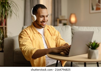 Young African American Man In Headphones Working Online, Using Laptop At Home Office, Copy Space. Happy Millennial Black Guy Surfing Internet, Communicating Online On Portable Pc