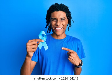 Young African American Man Holding Blue Ribbon Smiling Happy Pointing With Hand And Finger 