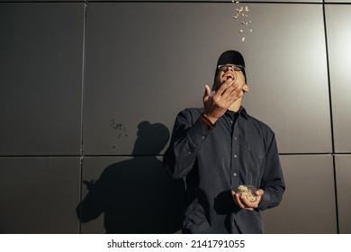 Young African American Man Holding Peanuts On Black Background Street