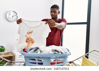 Young African American Man Holding Dirty Clothes At Laundry Room