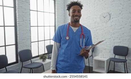 A young african american man in medical scrubs with a stethoscope and clipboard smiles confidently in a brightly lit hospital waiting room with chairs by large windows. - Powered by Shutterstock