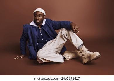 Young African American man sitting cross-legged on ground. - Powered by Shutterstock