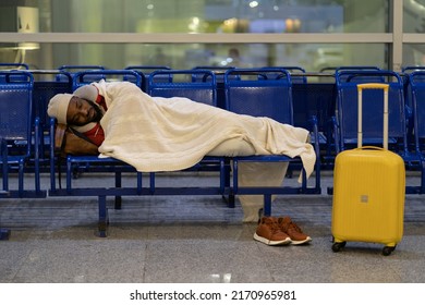 Young African American Man Sleeping Under Plaid, Waiting For Flight, Feel Cold. Black Guy Lying On Chairs In Airport Lounge, Sleep On An Uncomfortable Bench, Freezing. Long Night Connection. 