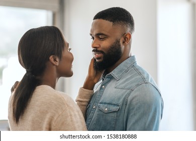 Young African American man smiling and looking at his wife while standing arm in arm together in their modern apartment - Shutterstock ID 1538180888