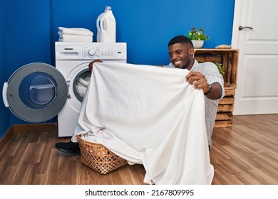 Young African American Man Smiling Washing Clothes At Laundry Room