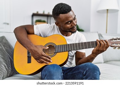 Young african american man smiling confident playing guitar at home - Powered by Shutterstock