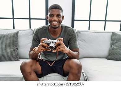 Young African American Man Smiling Confident Using Vintage Camera At Home