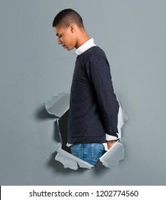 Young African American Man Standing And Looking Down Through A Paper Hole