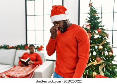 Young African American Man Standing By Christmas Tree Tired Rubbing Nose And Eyes Feeling Fatigue And Headache. Stress And Frustration Concept. 