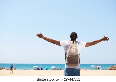 Young african american man standing with arms spread open at beach