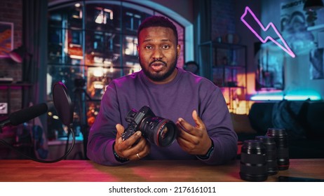 Young African American Man Talking Into Microphone While Recording A Podcast About New Photography Camera And Video Equipment. Confident Black Male Explaining New Features Live On Social Media.