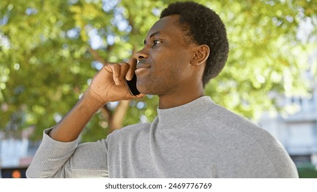 A young african american man talking on a smartphone outdoors, with nature in the background. - Powered by Shutterstock