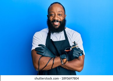 Young African American Man Tattoo Artist Wearing Professional Uniform And Gloves Holding Tattooer Machine Smiling With A Happy And Cool Smile On Face. Showing Teeth. 