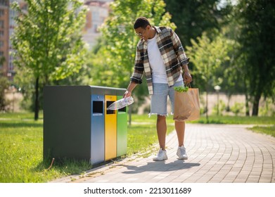 Young african american man throwing plastic bottle to the trash can