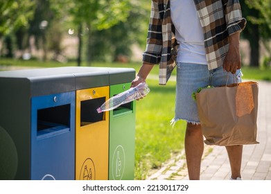 Young african american man throwing plastic bottle to the trash can - Powered by Shutterstock