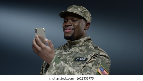 Young African American man from the US army talking on the mobile phone while deciding some problems on the dark wall background. - Powered by Shutterstock