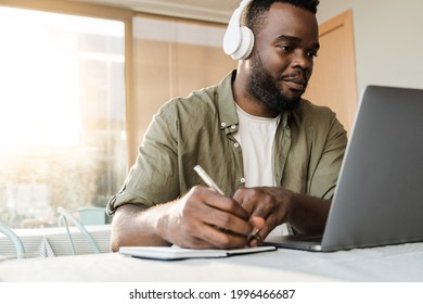 Young african american man using computer laptop while wearing headphones at bar restaurant - Conference video call lifestyle technology concept - Focus on face