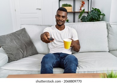 Young African American Man Watching Tv Drinking Coffee At Home