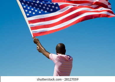 Young African American Man Waving A USA Flag On Beach