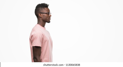 Young African American Man Wearing Pink T-shirt Looking To Side, Relax Profile Pose With Natural Face With Confident Smile.