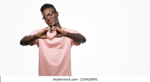 Young African American Man Wearing Pink T-shirt Smiling In Love Showing Heart Symbol And Shape With Hands. Romantic Concept.