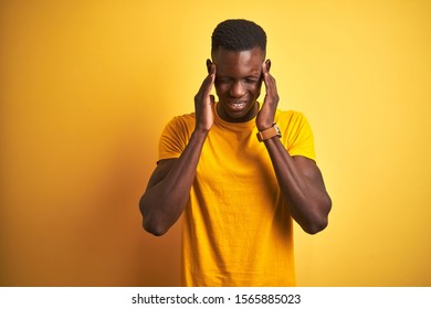 Young african american man wearing casual t-shirt standing over isolated yellow background with hand on headache because stress. Suffering migraine. - Shutterstock ID 1565885023