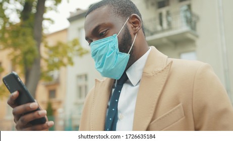 Young African American man wearing face mask look around use phone on street coronavirus safety protection pandemic outbreak medical mask slow motion - Powered by Shutterstock