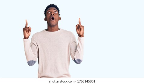 Young african american man wearing casual clothes amazed and surprised looking up and pointing with fingers and raised arms. 