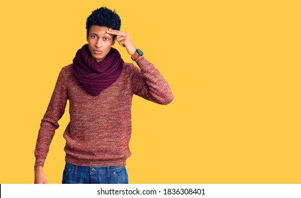 Young African American Man Wearing Casual Winter Sweater And Scarf Pointing Unhappy To Pimple On Forehead, Ugly Infection Of Blackhead. Acne And Skin Problem 