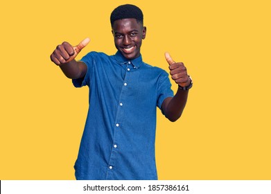 Young african american man wearing casual clothes approving doing positive gesture with hand, thumbs up smiling and happy for success. winner gesture. 