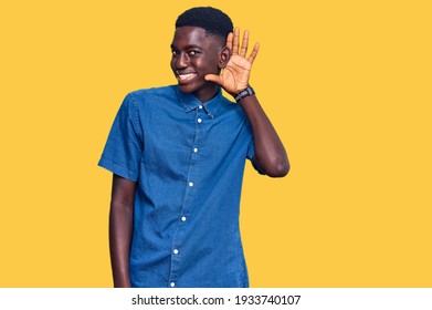 Young African American Man Wearing Casual Clothes Smiling With Hand Over Ear Listening An Hearing To Rumor Or Gossip. Deafness Concept. 