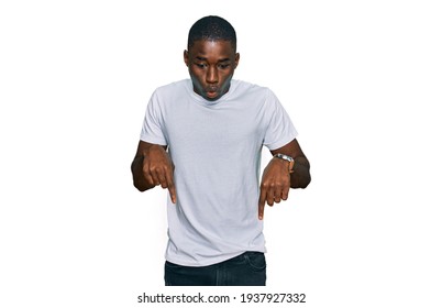 Young African American Man Wearing Casual White T Shirt Pointing Down With Fingers Showing Advertisement, Surprised Face And Open Mouth 