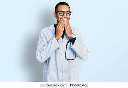 Young African American Man Wearing Doctor Uniform And Stethoscope Laughing And Embarrassed Giggle Covering Mouth With Hands, Gossip And Scandal Concept 
