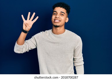 Young african american man wearing casual clothes showing and pointing up with fingers number four while smiling confident and happy. 