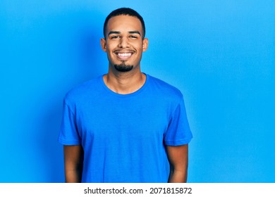 Young african american man wearing casual blue t shirt with a happy and cool smile on face. lucky person. 