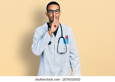 Young african american man wearing doctor uniform and stethoscope asking to be quiet with finger on lips. silence and secret concept. 